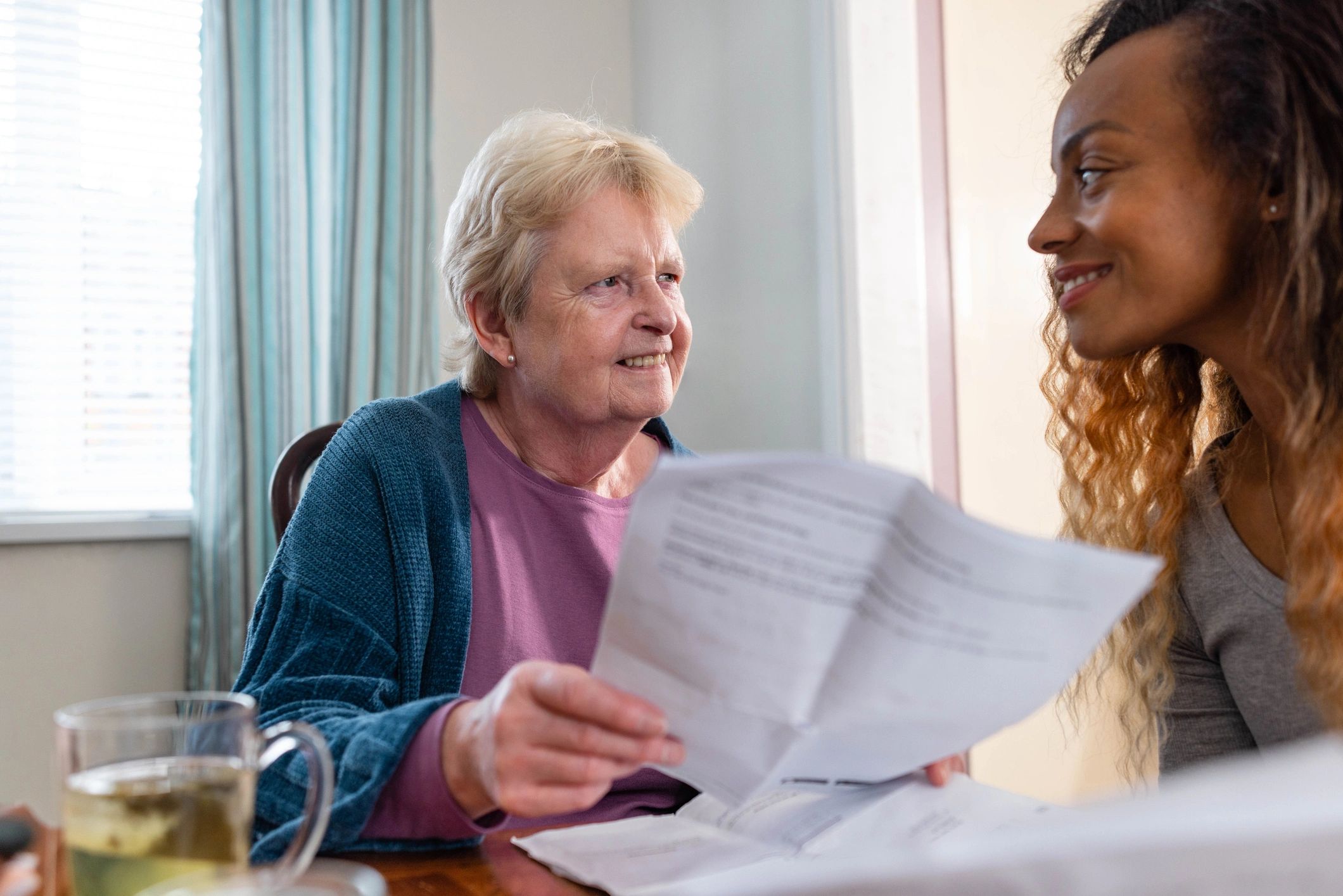 Adult daughter and grandmother reviewing a bill together at home