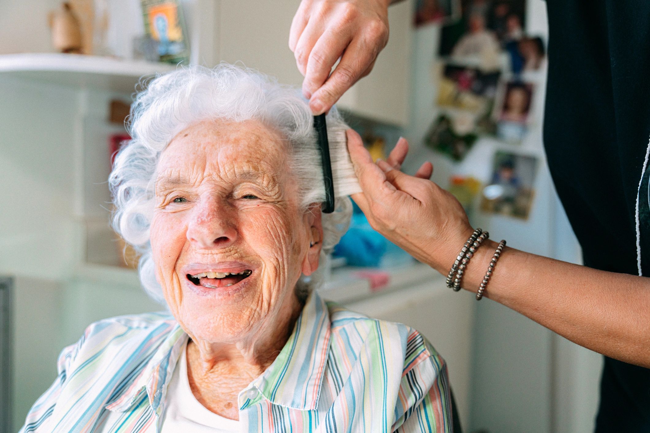 Caregiver helping a senior woman with grooming at home