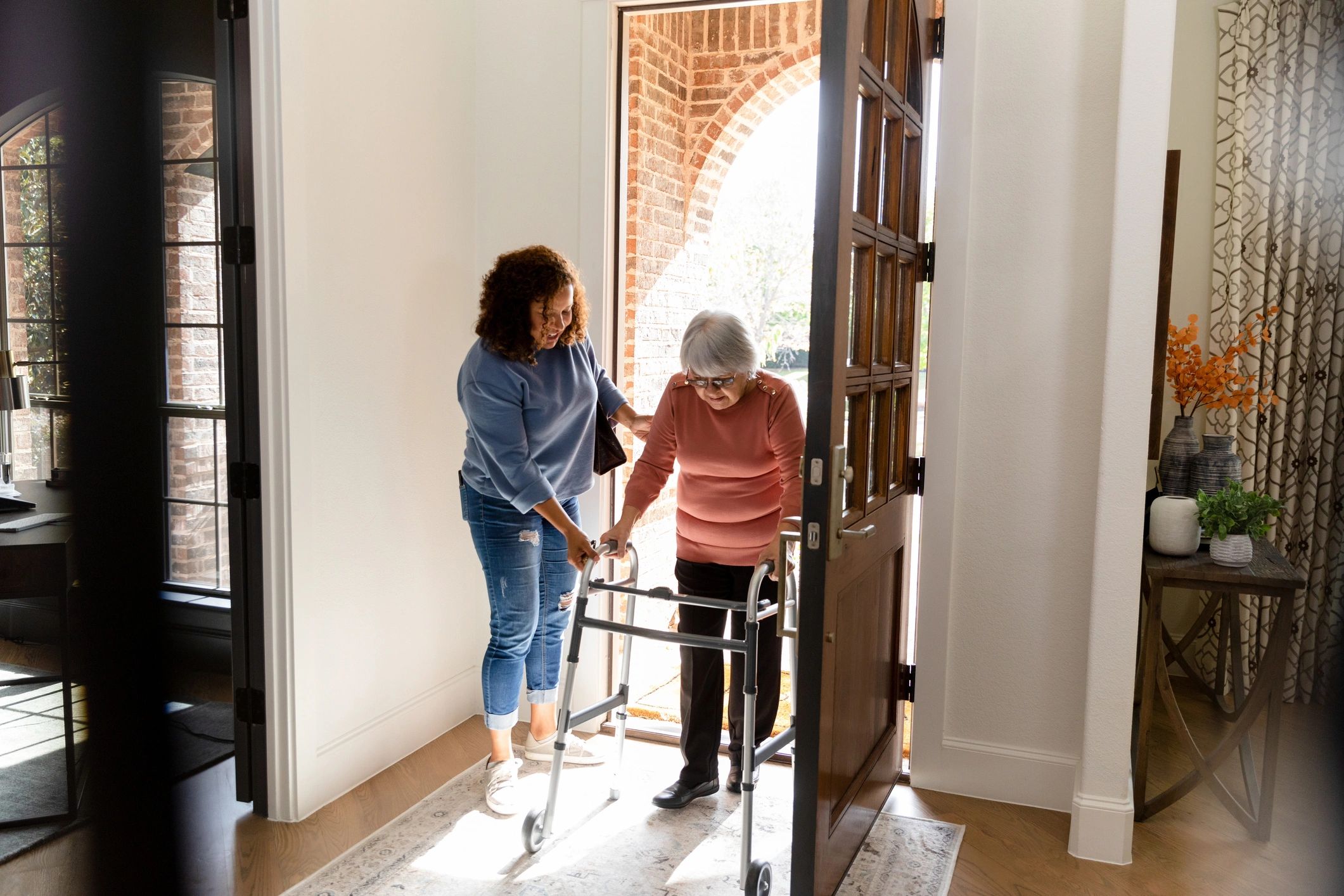Caregiver helping an older adult enter her home