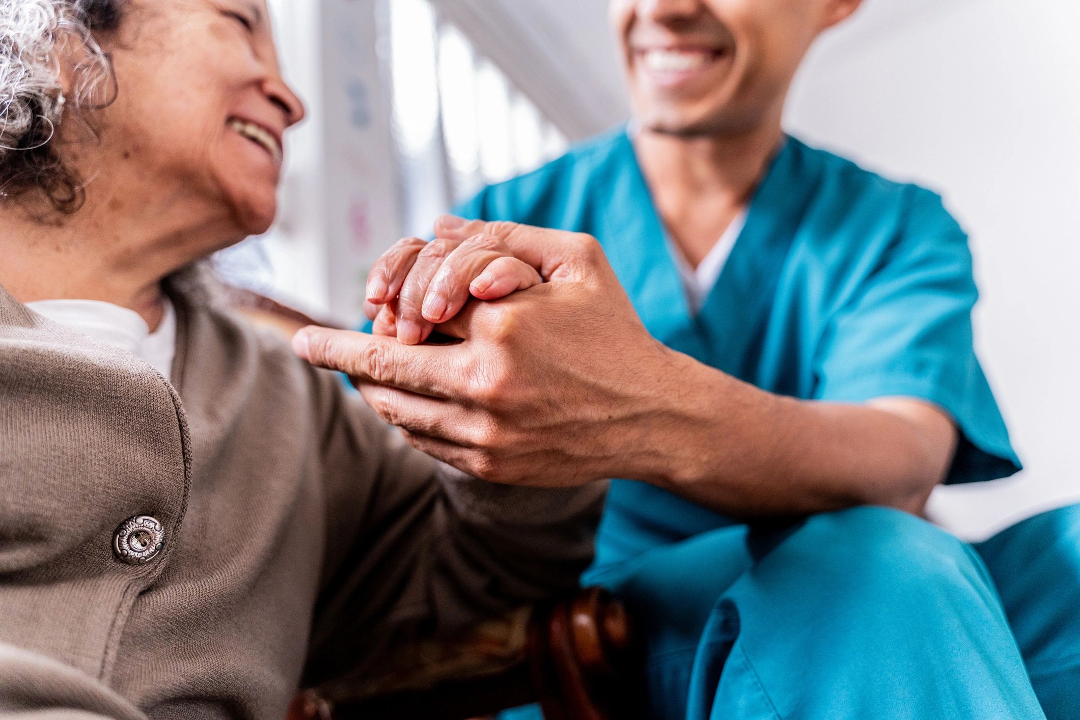 Caregiver holding a senior’s hands at home
