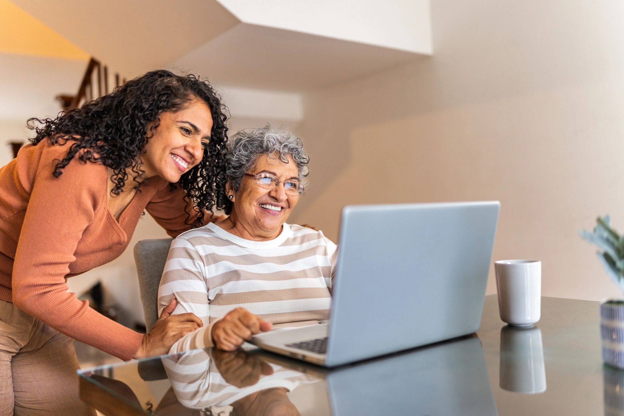 Senior woman using a laptop with support from family at home
