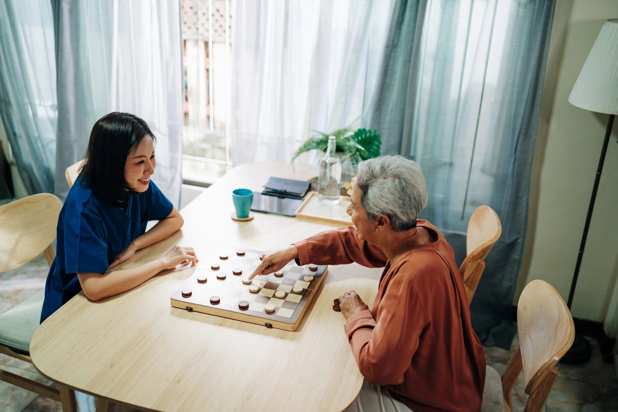 Caregiver and older adult playing a board game at home