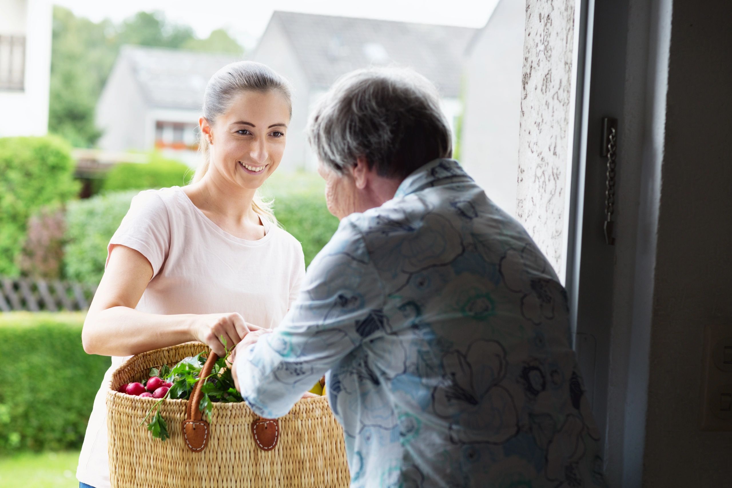 Caregiver delivering groceries to a senior at home